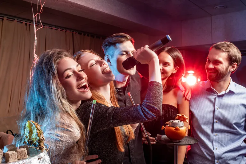 Freunde singen gemeinsam Karaoke auf einer Privatparty